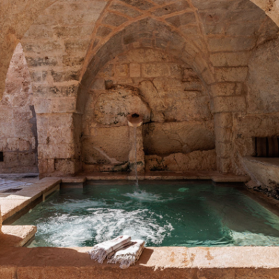 Stone covered hot spring pool with archways and a small waterfall.