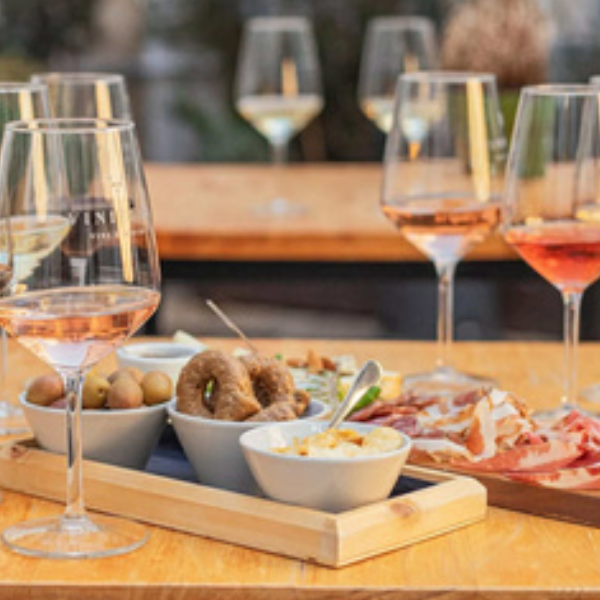 Table with wine glasses, olives, figs, and charcuterie platter on a wooden surface.